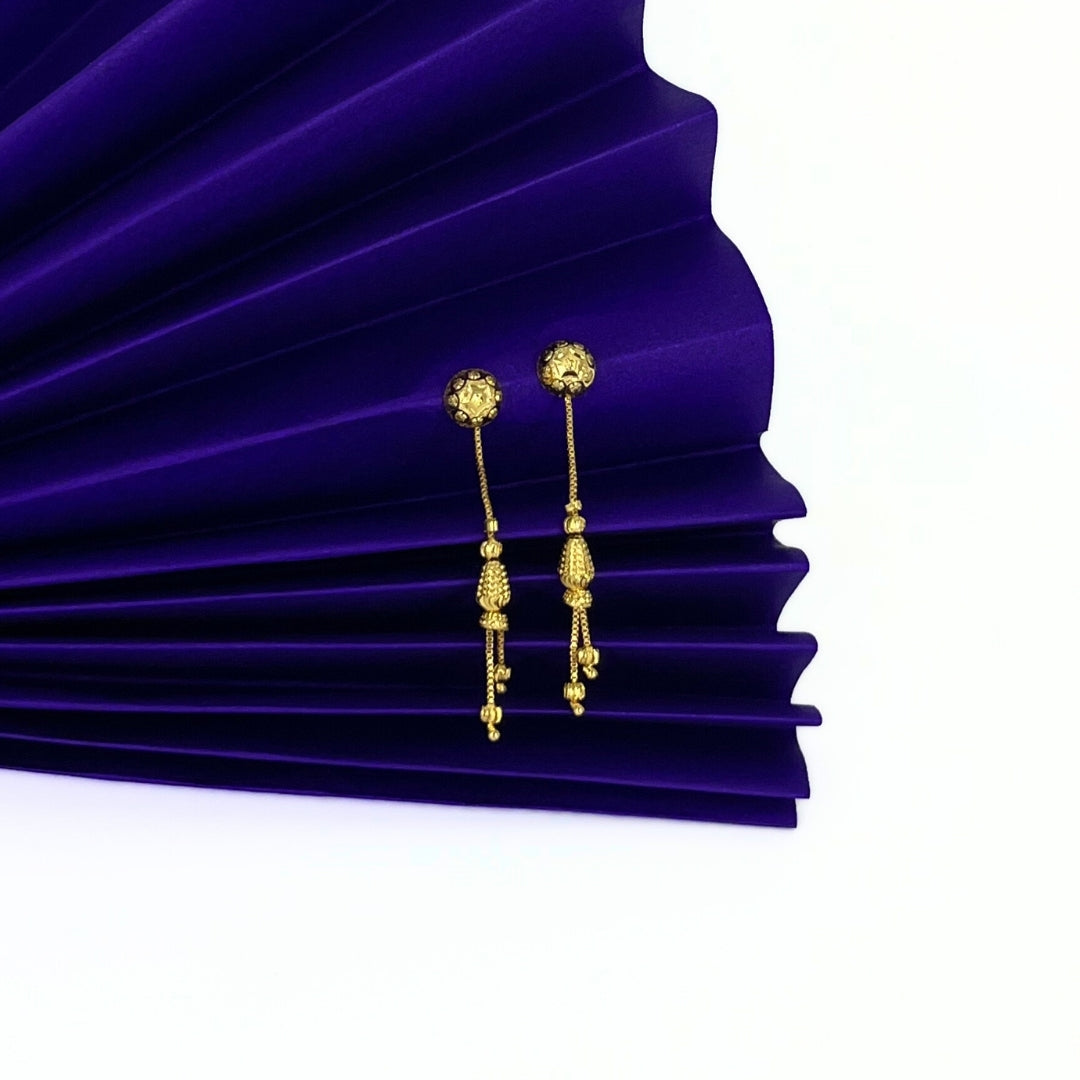 Nira Kalyani Gold plated sui dhaga earrings on a purple pleated fabric background