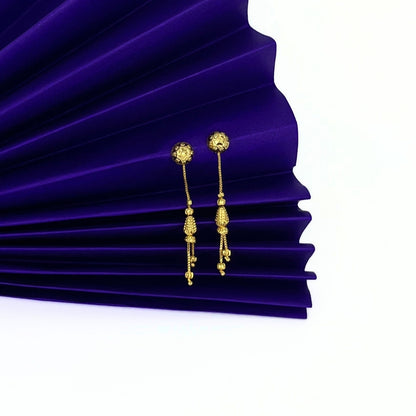 Nira Kalyani Gold plated sui dhaga earrings on a purple pleated fabric background