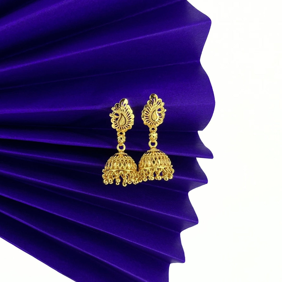 nira kalyani gold jhumka earrings on a purple pleated fabric background