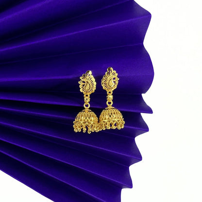 Nira Kalyani Gold jhumka earrings on a purple pleated fabric background